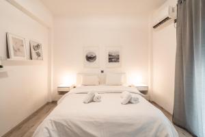 um quarto branco com uma cama branca com 2 toalhas em Urban Serenity Gem in Kallithea neighbourhood! em Atenas
