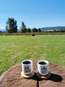 dos tazas de café sentadas encima de una mesa en Drewniane domki z balią i widokiem na Góry - Klimatyczny Kompleks w Górach Izerskich #Widogruszka, en Grudza