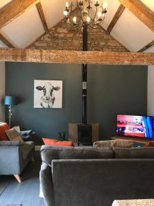 a living room with a couch and a tv at Elishaw Farm Holiday Cottages in Otterburn