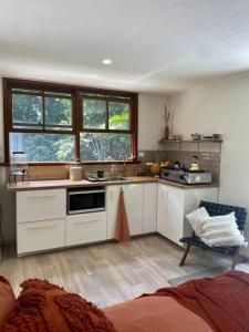 a kitchen with white cabinets and a sink and windows at Tranquil Rainforest Studio Kuranda in Kuranda