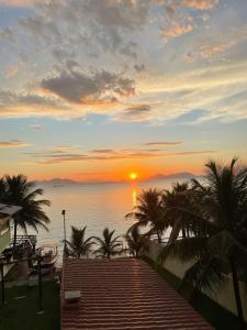 a sunset over the water with palm trees and a dock at Casa para temporada com vista para o Mar in Mangaratiba +18 photos