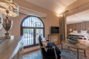 a living room with a large window and a bed at Suites Murillo Catedral in Seville