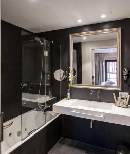 a bathroom with a sink, mirror, and bathtub at Suites Murillo Catedral in Seville