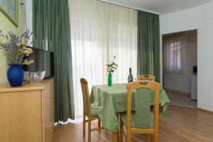 a dining room table with a green tablecloth and a television at Marija F2 Apartment in Krk