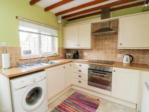 a kitchen with a washing machine and a sink at Keepers Cottage, 21 Coppergate in Nafferton