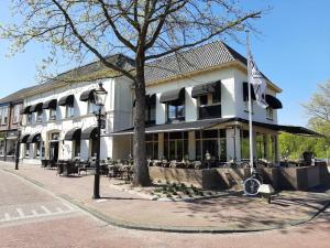 ein weißes Gebäude mit einem Baum davor in der Unterkunft De Zwaan Delden in Delden