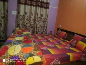 a bed with a colorful comforter in a bedroom at Laxmi Homes in Sari