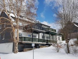 a house with a deck in the snow at Altastenberger Lodge in Winterberg