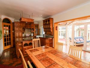 a kitchen with a wooden table and a dining room at Ballysheen House in Rosslare