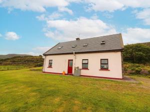 una piccola casa bianca con una porta rossa su un prato di Fraoch a Waterville