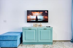 Armario azul con fregadero y TV en la pared en Summer Dream Beach Apartment, en Mamaia Nord – Năvodari