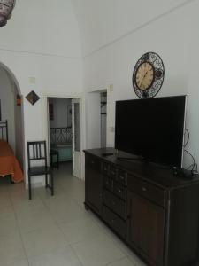 a living room with a tv and a clock on a dresser at Vico Anglani Guest House in Ostuni