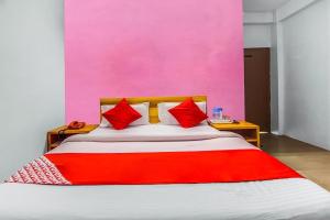a bed with red pillows and a pink wall at Shillong Guest House in Shillong