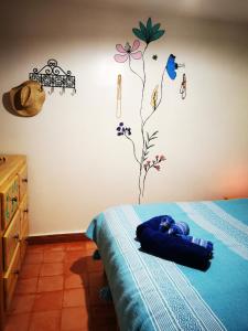 1 dormitorio con 1 cama con sábana azul y una flor en la pared en Tigmi Blue - Imsouane Surf et Océan, en Imsouane