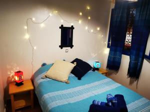 1 dormitorio con 1 cama con luces en la pared en Tigmi Blue - Imsouane Surf et Océan, en Imsouane