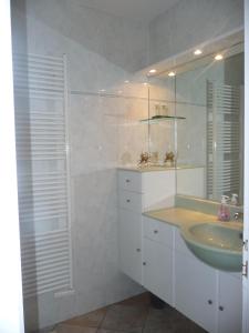 Baño blanco con lavabo y espejo en Maison de Line en LʼÎle-dʼOlonne