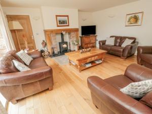 sala de estar con muebles de cuero y chimenea en The Red Barn, en Longframlington