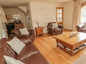 sala de estar con muebles de cuero y mesa de centro en The Red Barn, en Longframlington