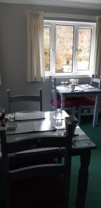a dining room with a table and chairs and two windows at Lothlorien in Fort William