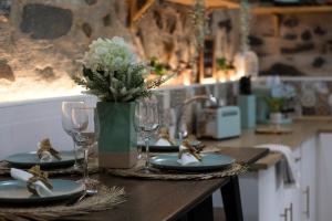 a table with plates and glasses and a vase with flowers at Salgueiral Guest House Douro in Peso da Régua