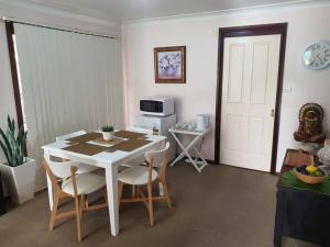 a room with a table and chairs and a microwave at The Junction Estate COOL CALM COZY A Home N Host Property in Wallerawang