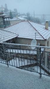 een huis met een met sneeuw bedekt dak en een hek bij House in a village of Taygetus in Sparta