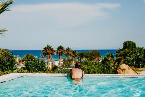 mężczyzna siedzący w basenie patrzący na ocean w obiekcie Alannia Els Prats w mieście Montroig