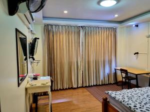 ein Schlafzimmer mit einem Bett und einem Schreibtisch mit einem Fernseher in der Unterkunft T2B Hostel in Chiang Mai