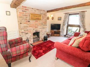 a living room with a red couch and a fireplace at Church Farm Cottage in Clifton