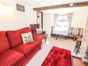 sala de estar con sofá rojo y mesa en Church Farm Cottage, en Clifton