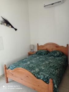 - une chambre avec un lit en bois et une couette verte dans l'établissement Maisonnette U Santu Ghjuvandria ou A Santa Ghjulia entre mer et Montagne, à Volpajola