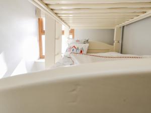 Cama blanca en habitación con ventana en Keeper's Cottage, en Moelfre