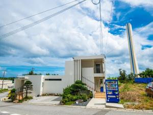 a white building with a sign in front of it at Kugani-YA. in Kin