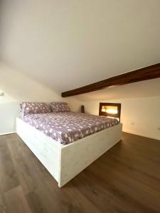 een groot bed in een kamer met een houten vloer bij Appartamento Casaliva sul Garda in Pulciano