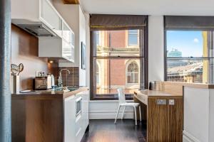 a kitchen with a counter and a table and some windows at Roomzzz Manchester City in Manchester