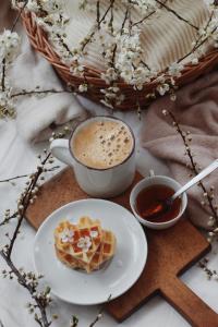 a table with a cup of coffee and a plate of waffles at MEA Centre Apartment in Shkodër