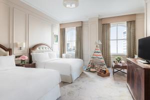 a hotel room with two beds and a christmas tree at The Langham London in London