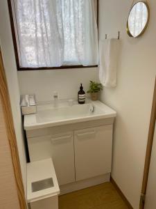 uma casa de banho com um lavatório branco e um espelho. em ゲストハウスHINATA em Hyuga