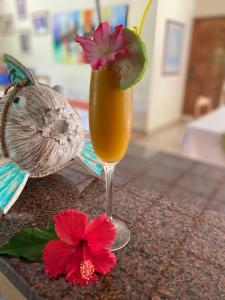 een drankje in een glas met een bloem op de toonbank bij Calou Guest House in La Digue