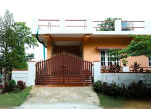 a house with a wooden gate in front of it at Srishti Homestay in Madikeri