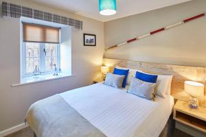 een slaapkamer met een groot wit bed met blauwe kussens bij Host & Stay - The Watchtower in Bamburgh