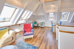een zolderkamer met een bank, stoelen en ramen bij Host & Stay - The Watchtower in Bamburgh