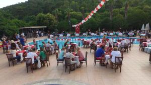 a group of people sitting around a swimming pool at RİOS BEACH HOTEL in Beldibi