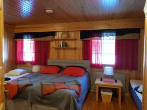 1 dormitorio con 2 camas y cortinas rojas en Tunturipöllö / Lapland, Saariselkä, en Saariselkä
