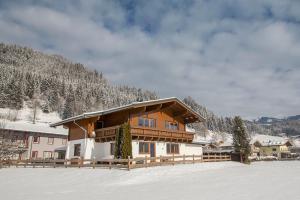 una casa en la nieve frente a una montaña en Chalet Dorfkristall en Bramberg am Wildkogel