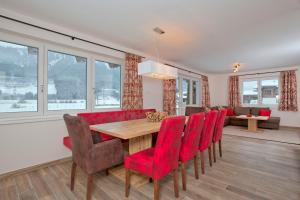 a dining room with a table and red chairs at Chalet Dorfkristall in Bramberg am Wildkogel
