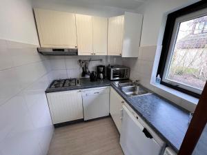a kitchen with white cabinets and a sink and a window at Beautifull house Beach Life 47 in De Cocksdorp