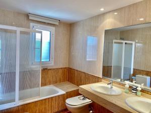 a bathroom with two sinks and a tub and a toilet at Casa con vistas al mar in El Vendrell