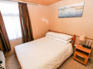 a small bedroom with a bed and a window at Puffin Chalet in Roch