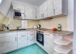 班辛海的住宿－Seehof Wohnung 1.33，厨房配有白色橱柜和水槽